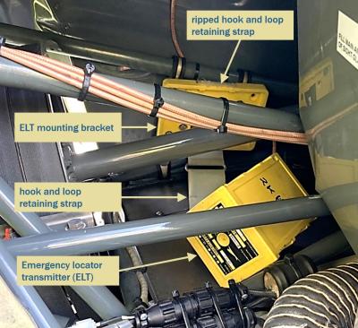 Annotated photo from the report. Interior view of the helicopter's upper frame assembly as it was found after the accident. The ELT mounting bracket is attached ot the airframe. The ELT itself hangs below, out of position. The hook-and-loop strap that kept the ELT in place on its mounting bracket is shown ripped.