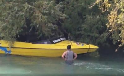 Photo of yellow jet boat caught in trees overhanging river