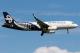 Air New Zealand Airbus A320 aircraft ZK-OXJ in flight with landing gear extended, approaching for landing against a blue sky. The aircraft features a distinctive black-and-white koru fern livery.