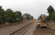 Workers in orange high-vis on a train track near a level crossing