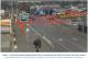 Fig1 from report. still image from CCTV, depicting the incident. An urban low-level light industrail area. Selwyn street is in the centre of the view from foreground to distance. The level crossing is in the middle. A bus has clearly just crossed the level crossing, travelling away from the camera view. A locomotive approaches the bus, approximately twelve metres away
