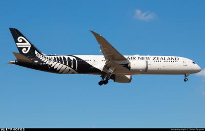 Air New Zealand Boeing 787-9 Dreamliner, registration ZK-NZR, in black and white koru and fern livery, flying with landing gear extended against a clear blue sky