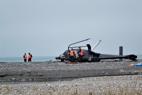 Photo - TAIC investigators inspect the helicopter wreckage on the beach