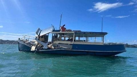 photo of the ferry - about 13 metres long - soon after the accident, still afloat. The port side is in splinters and the wheelhouse is destroyed. Photo of the stricken ferry, a 44' wooden construction vessel with a 'classic' look, built in 1944. View is square-on to the port side. Almost all of the port side above the waterline and forward of amidship is a mess of fractured timber and splinters, as is the wheelhouse and the forward part of the open shelter for passengers. 